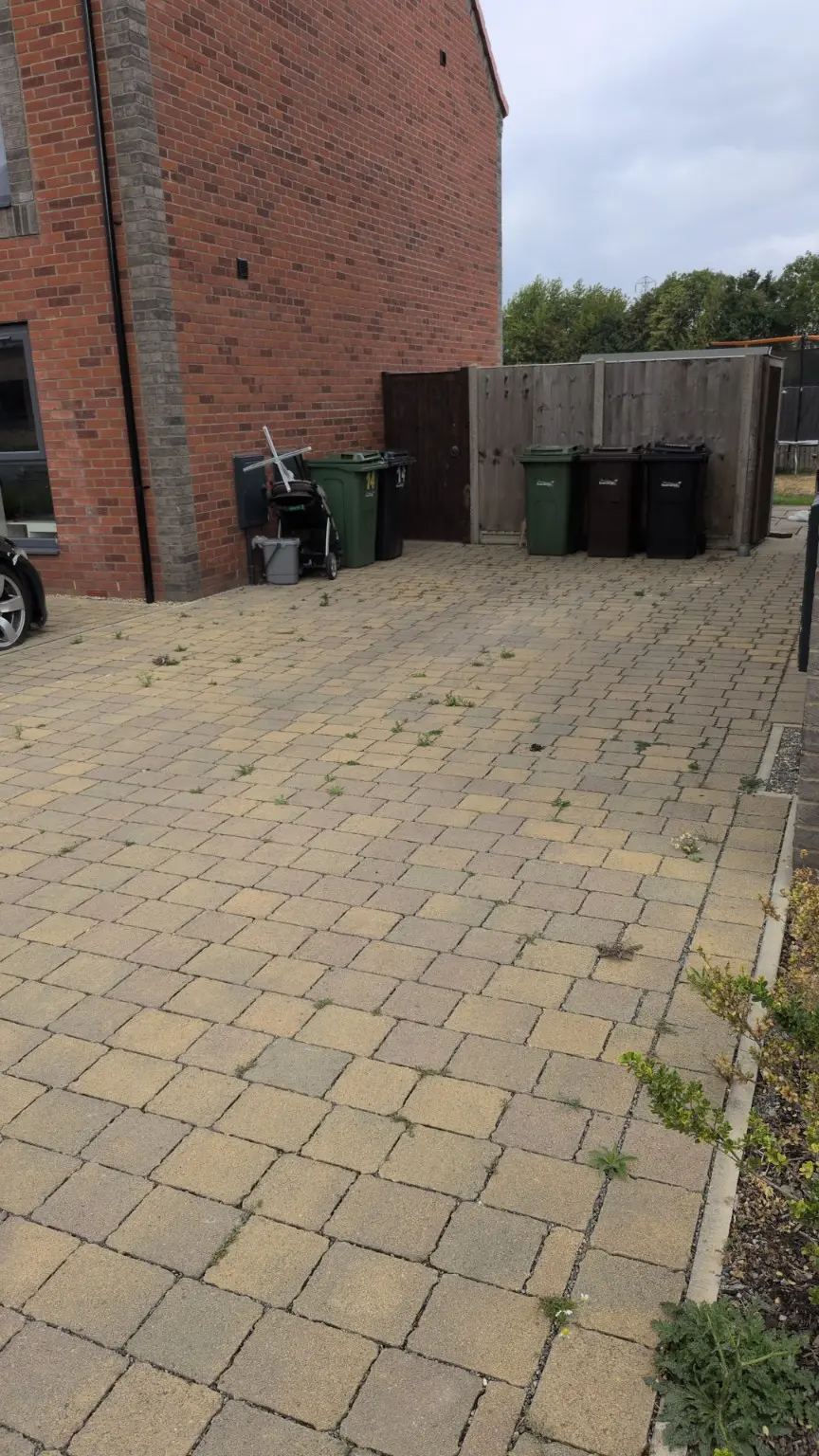 Block-paved driveway with weeds and surface build-up before pressure washing
