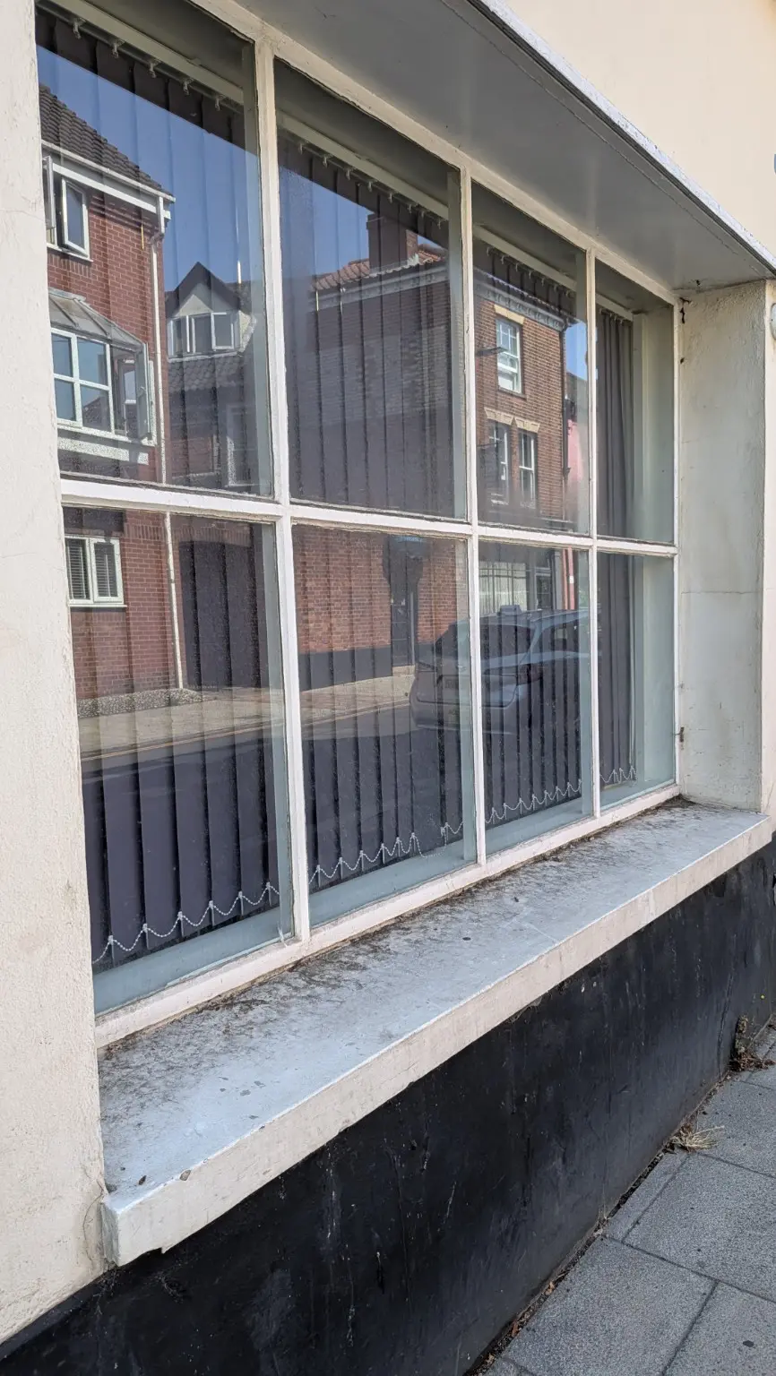 Large multi-pane window and sill with surface dirt before professional cleaning