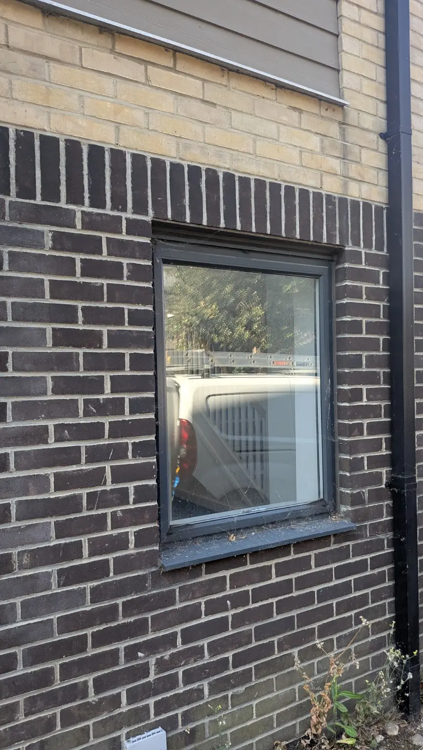 Dark-framed ground-floor window before professional cleaning